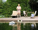 Eigentümer mit funkgesteuertem Modellboot am Schwimmteich