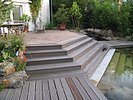 5 Stufen führen von der Holzdeckterrasse zum Schwimmteich