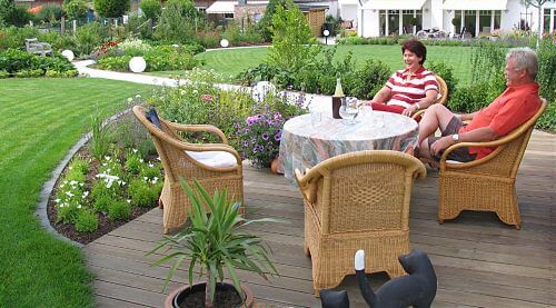 Mann und Frau auf neuer Holzterrasse im landschaftlichen Garten nach der Gartenplanung