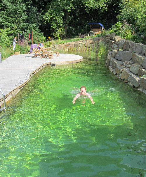 Schwimmteich mit Holzterrasse und Natursteinwand